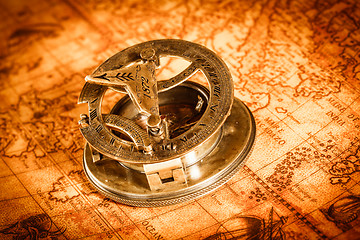 Image showing Vintage compass lies on an ancient world map.