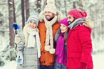 Image showing smiling friends with smartphone in winter forest