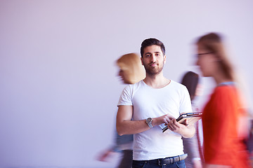 Image showing student working on tablet, people group passing by