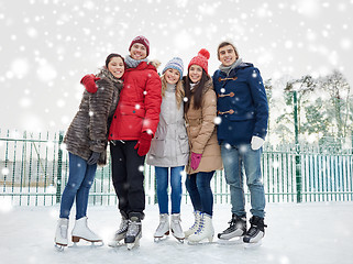 Image showing happy friends ice skating on rink outdoors