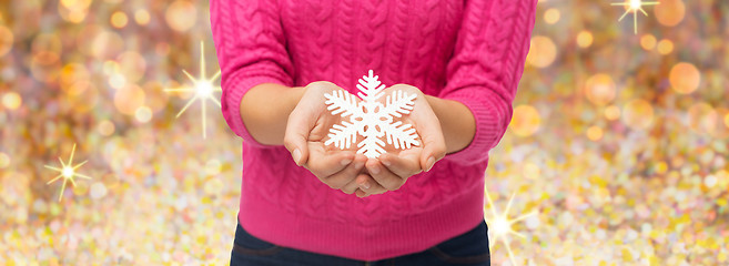 Image showing close up of woman in sweater holding snowflake