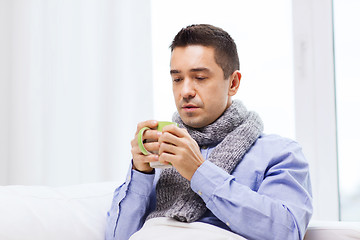 Image showing ill man with flu drinking hot tea from cup at home