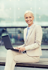 Image showing smiling businesswoman working with laptop outdoors