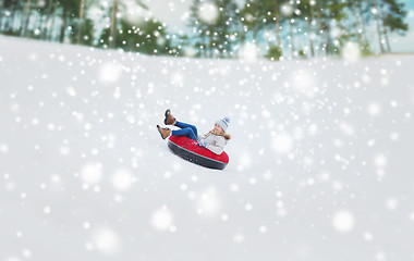 Image showing happy teenage girl sliding down on snow tube