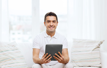 Image showing smiling man working with tablet pc at home