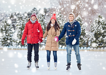 Image showing happy friends ice skating on rink outdoors