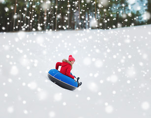 Image showing happy teenage girl sliding down on snow tube