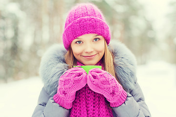 Image showing smiling young woman with cup in winter forest