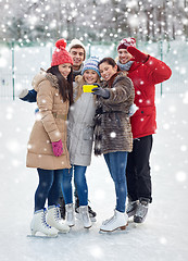 Image showing happy friends with smartphone on ice skating rink