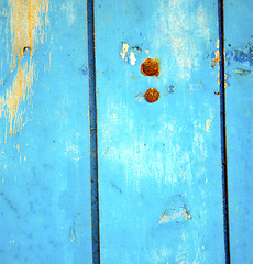 Image showing dirty stripped paint in the blue wood door and rusty nail