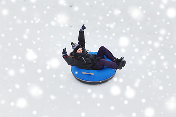 Image showing happy young man sliding down on snow tube