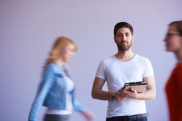 Image showing student working on tablet, people group passing by