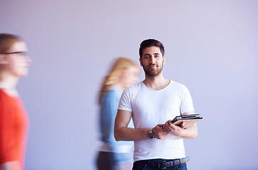 Image showing student working on tablet, people group passing by