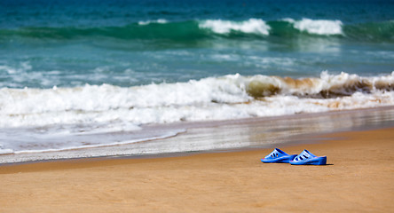 Image showing Women\'s Blue Slippers on a Sandy Ocean Beach