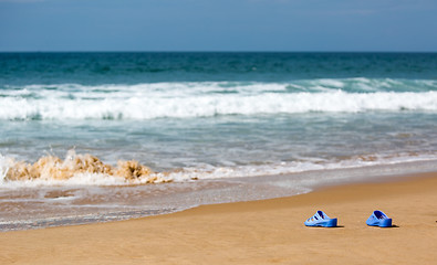 Image showing Women\'s Blue Slippers on a Sandy Ocean Beach