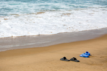 Image showing Women\'s and Men\'s Slippers on a Sandy Ocean Beach