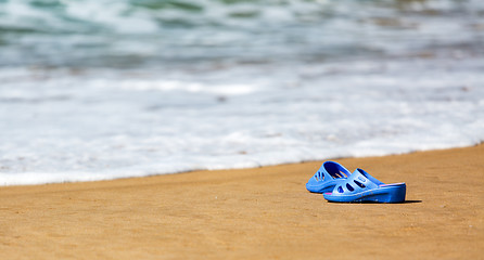 Image showing Women\'s Blue Slippers on a Sandy Ocean Beach