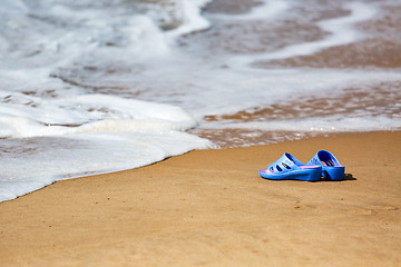 Image showing Women\'s Blue Slippers on a Sandy Ocean Beach