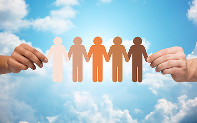 Image showing hands holding chain of people pictogram over sky