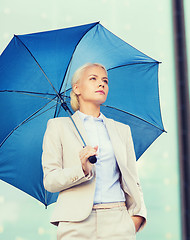 Image showing young serious businesswoman with umbrella outdoors