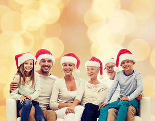 Image showing happy family in santa helper hats sitting on couch