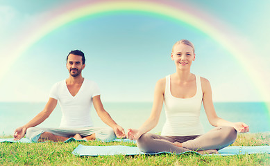 Image showing smiling couple making yoga exercises outdoors