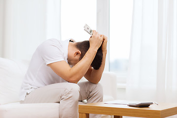 Image showing man with money and calculator at home