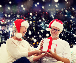 Image showing happy senior couple in santa hats with gift box