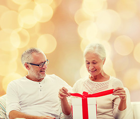 Image showing happy senior couple with gift box at home