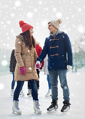 Image showing happy friends ice skating on rink outdoors