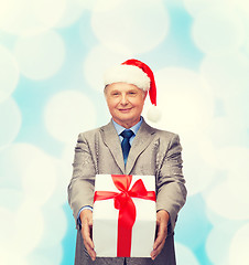 Image showing smiling man in suit and santa helper hat with gift