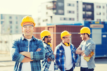 Image showing group of smiling builders in hardhats outdoors