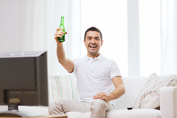 Image showing smiling man watching tv and drinking beer at home