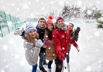 Image showing happy friends with smartphone on ice skating rink