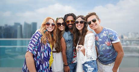 Image showing happy hippie friends with selfie stick over city