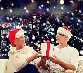 Image showing happy senior couple in santa hats with gift box