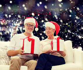 Image showing happy senior couple in santa hats with gift boxes