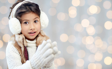 Image showing happy little girl in earmuffs over holidays lights