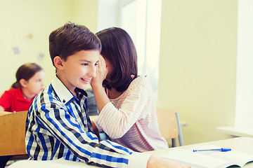 Image showing smiling schoolgirl whispering to classmate ear