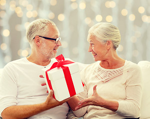 Image showing happy senior couple with gift box at home