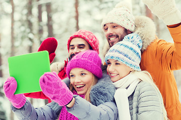 Image showing smiling friends with tablet pc in winter forest