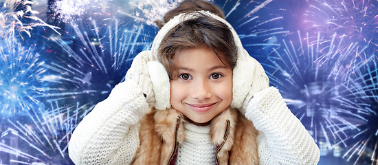 Image showing happy little girl wearing earmuffs over firework