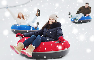 Image showing group of happy friends sliding down on snow tubes