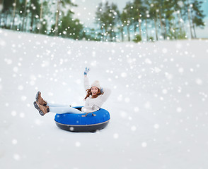 Image showing happy teenage girl sliding down on snow tube