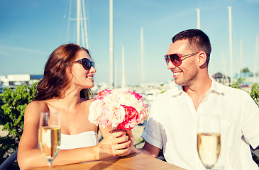 Image showing smiling couple with bunch and champagne at cafe