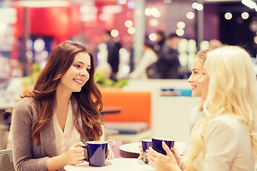 Image showing smiling young women drinking coffee in mall 