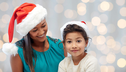 Image showing happy mother and little girl in santa hats at home