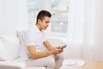 Image showing man with papers and calculator at home