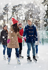 Image showing happy friends ice skating on rink outdoors