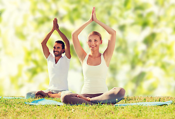 Image showing smiling couple making yoga exercises outdoors